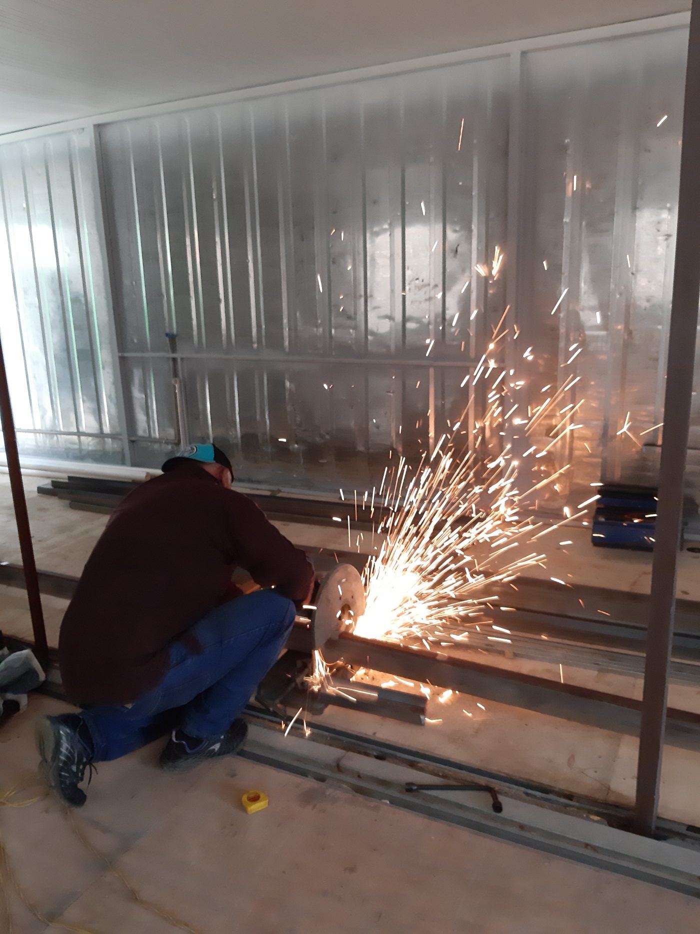 Worker cutting steel framing inside a container, sparks flying